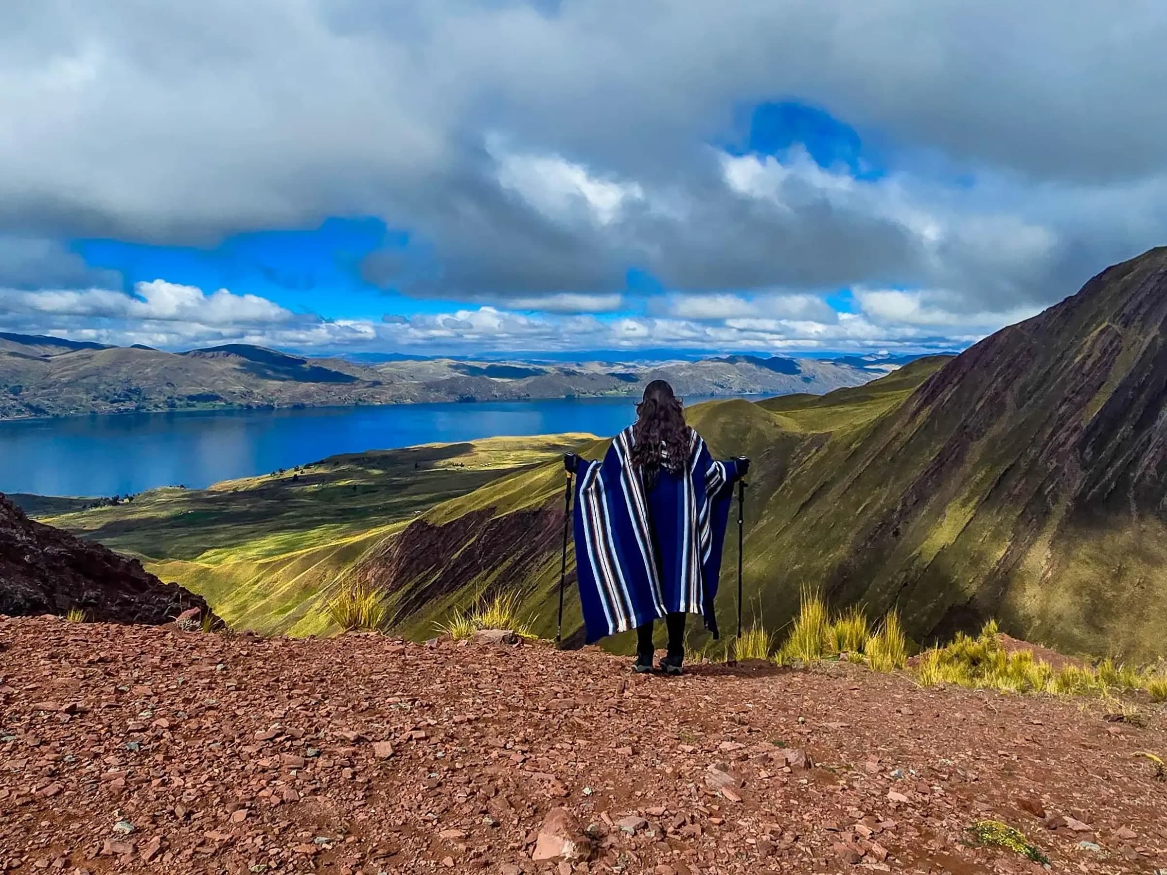 A traveller on a high ridge with a lake spread out in the valley below